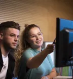 jongen en meisje achter latop meisje wijst naar laptop